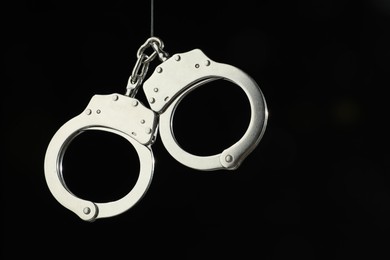 Photo of Metal chain handcuffs on black background, closeup