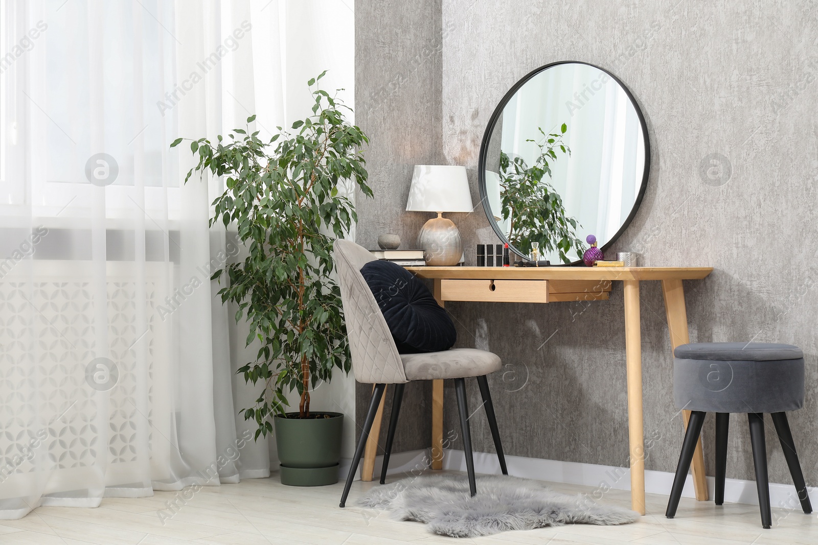 Photo of Mirror, dressing table, lamp, chair and houseplant indoors. Interior design