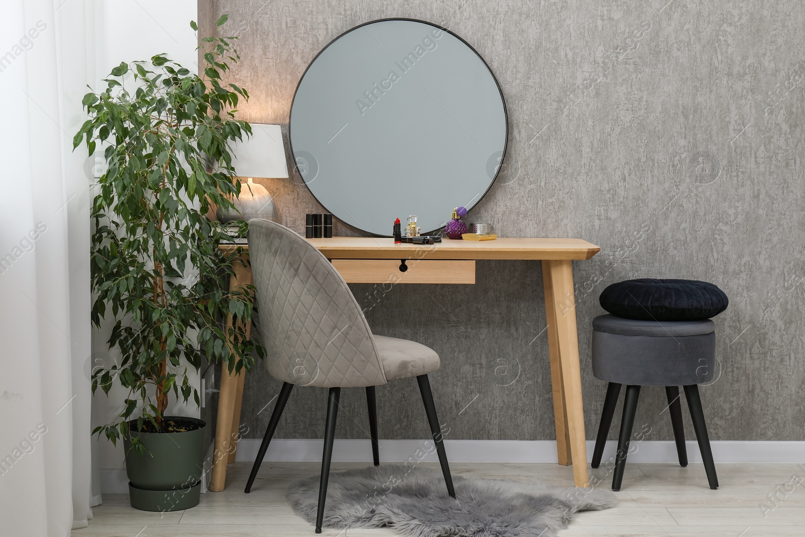 Photo of Mirror, dressing table with cosmetic products, lamp, chairs and houseplant indoors. Interior design