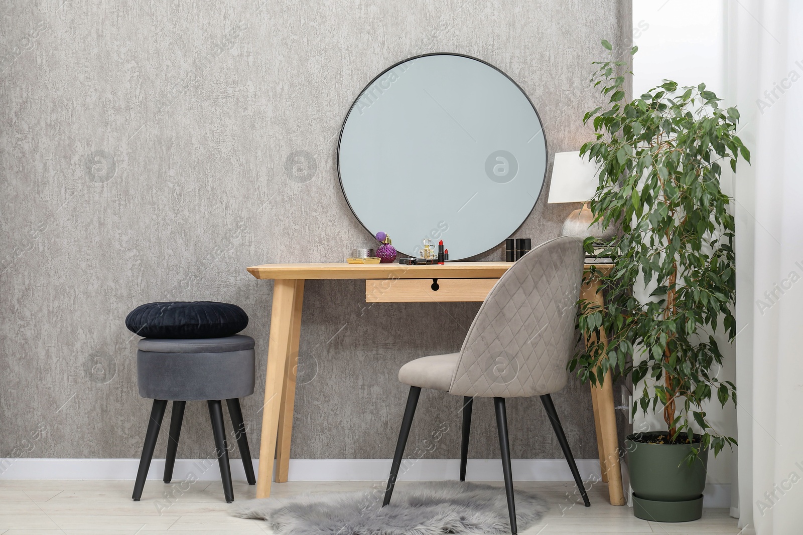 Photo of Mirror, dressing table with cosmetic products, lamp, chairs and houseplant indoors. Interior design