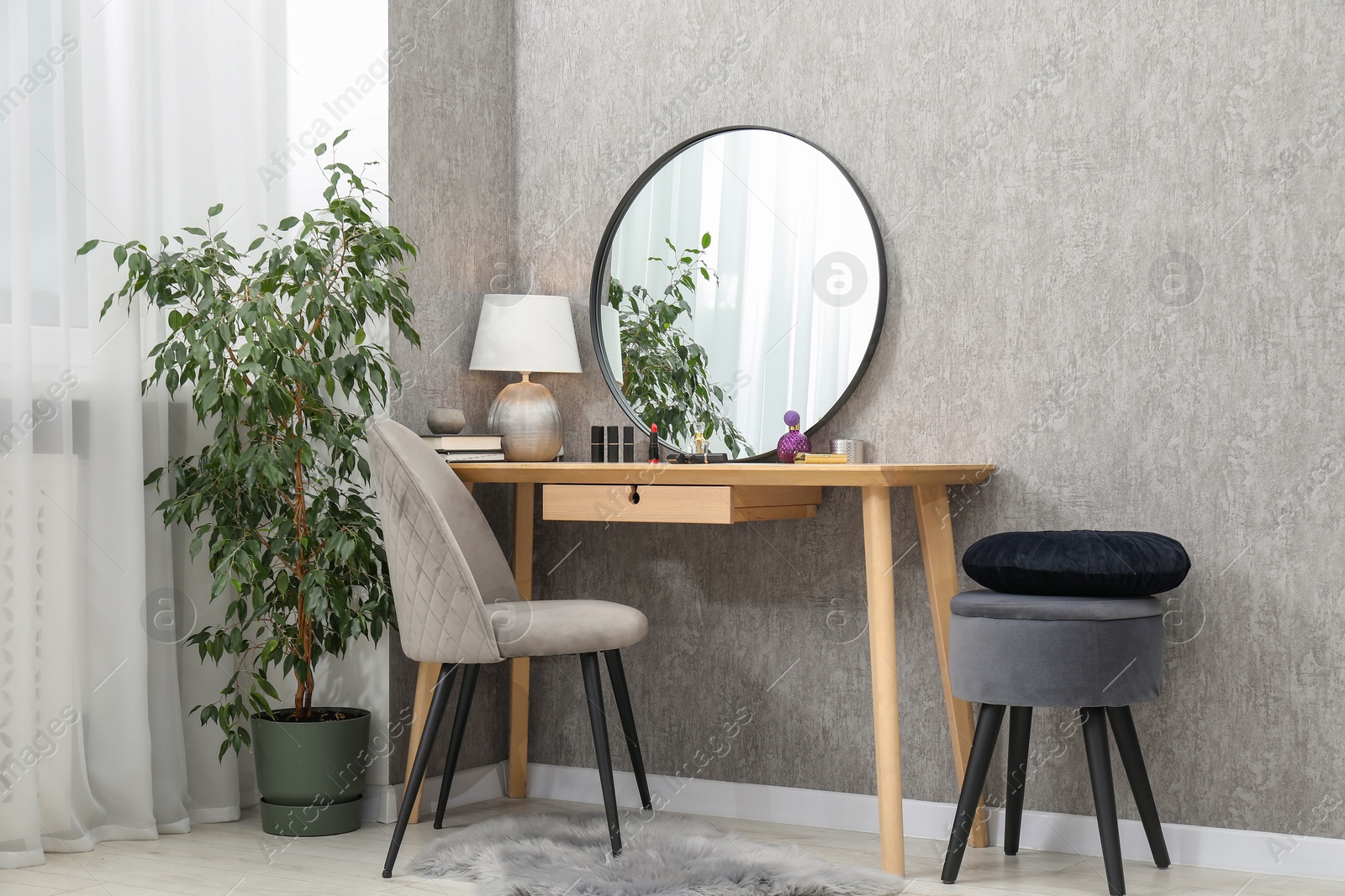 Photo of Mirror, dressing table with cosmetic products, lamp, chairs and houseplant indoors. Interior design