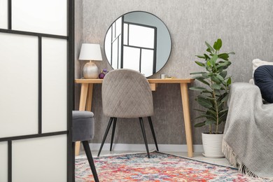 Mirror, dressing table, chair, houseplant and folding screen indoors. Interior design