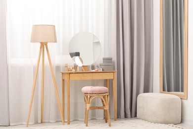 Photo of Mirrors, dressing table, lamp and stool near window indoors. Interior design