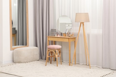 Photo of Mirrors, dressing table, lamp and stool near window indoors. Interior design