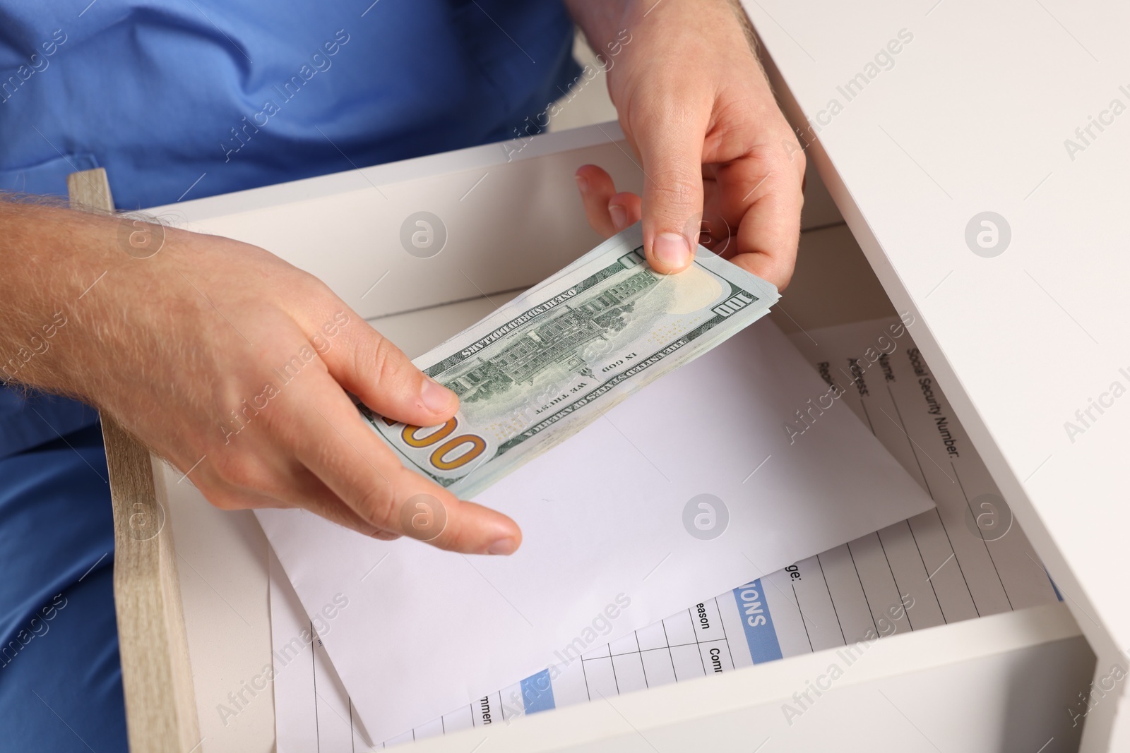 Photo of Corruption concept. Doctor putting dollar banknotes into drawer, closeup