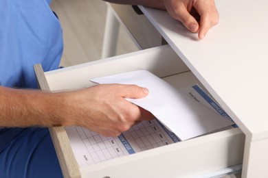 Corruption concept. Doctor putting envelope with money into drawer, closeup