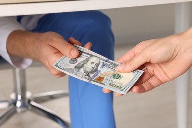 Photo of Corruption concept. Woman giving dollar banknotes to man under table, closeup