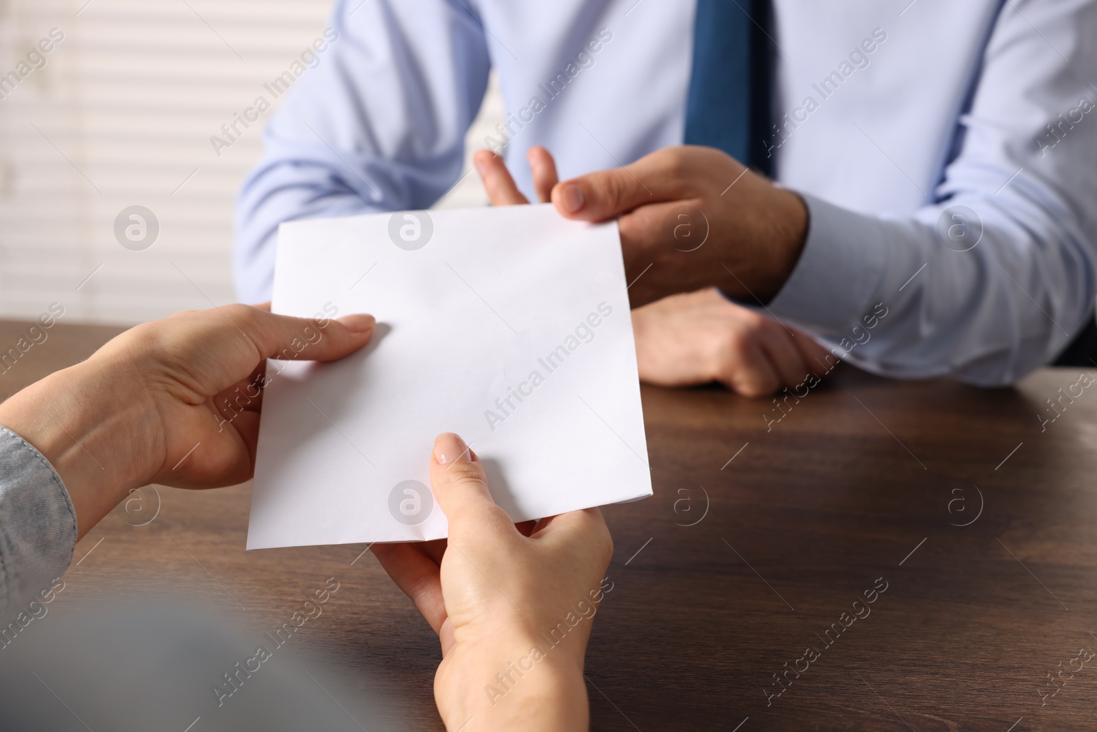 Photo of Corruption concept. Woman giving envelope with money to man at wooden table, closeup