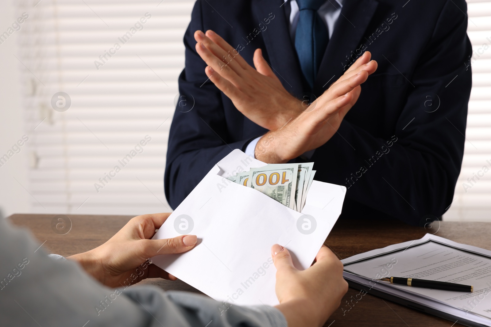 Photo of Corruption concept. Woman giving envelope with money to man at wooden table, closeup