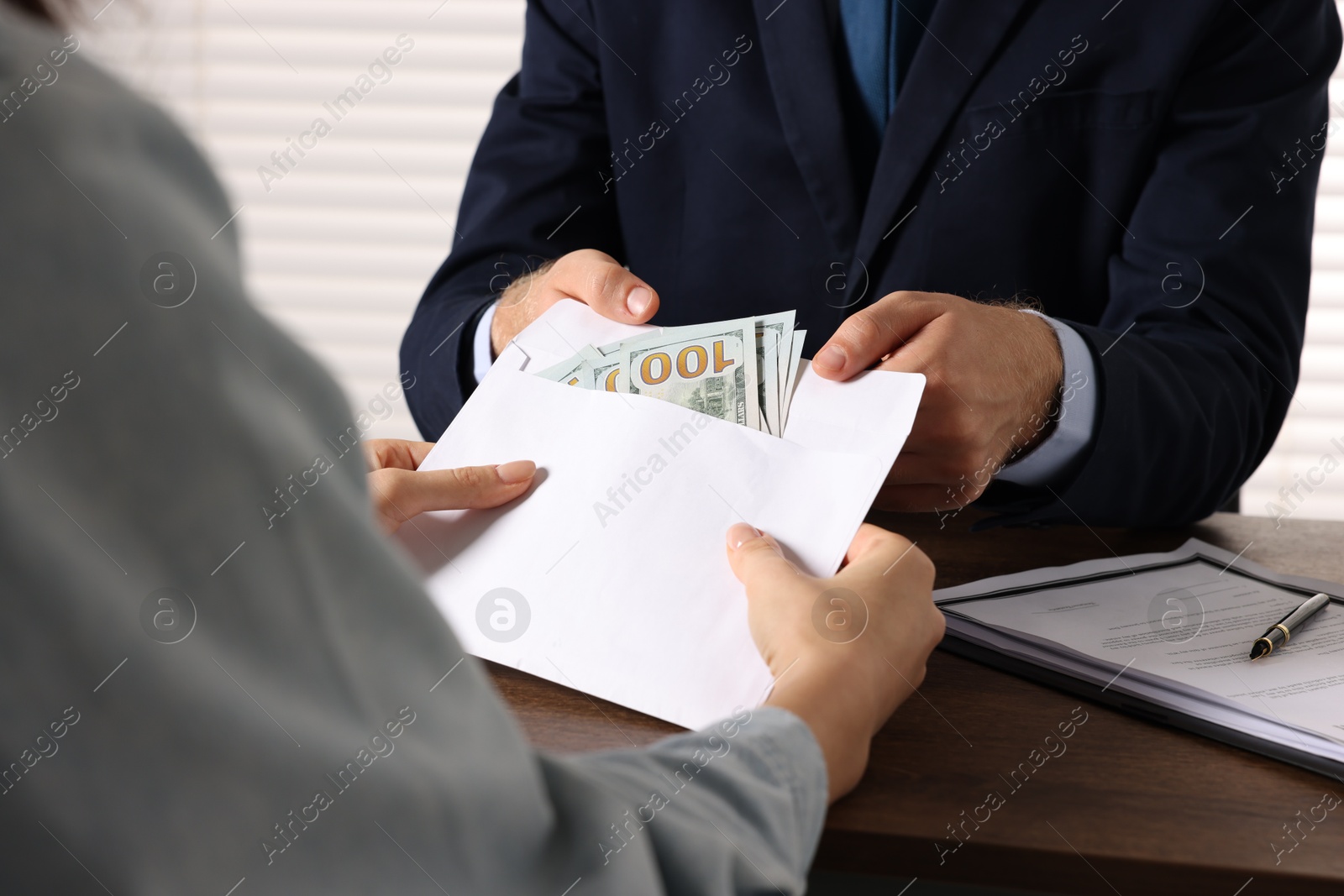 Photo of Corruption concept. Woman giving envelope with money to man at wooden table, closeup