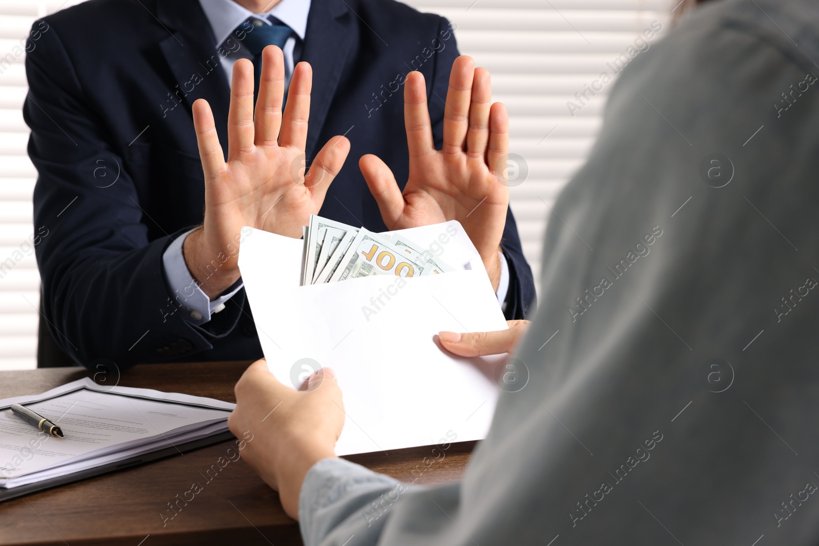 Photo of Corruption concept. Woman giving envelope with money to man at wooden table, closeup