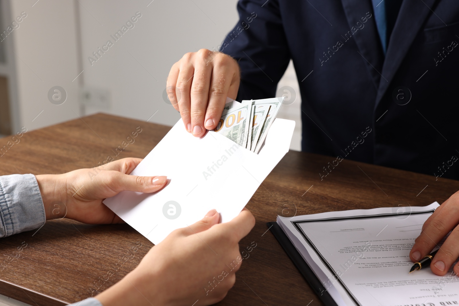 Photo of Corruption concept. Woman giving envelope with money to man at wooden table, closeup