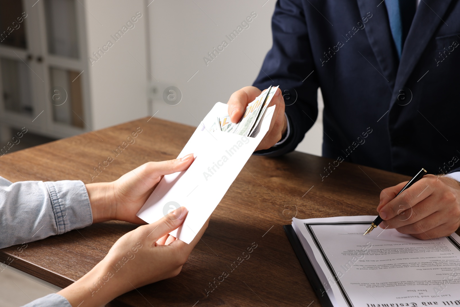 Photo of Corruption concept. Woman giving envelope with money to man at wooden table, closeup