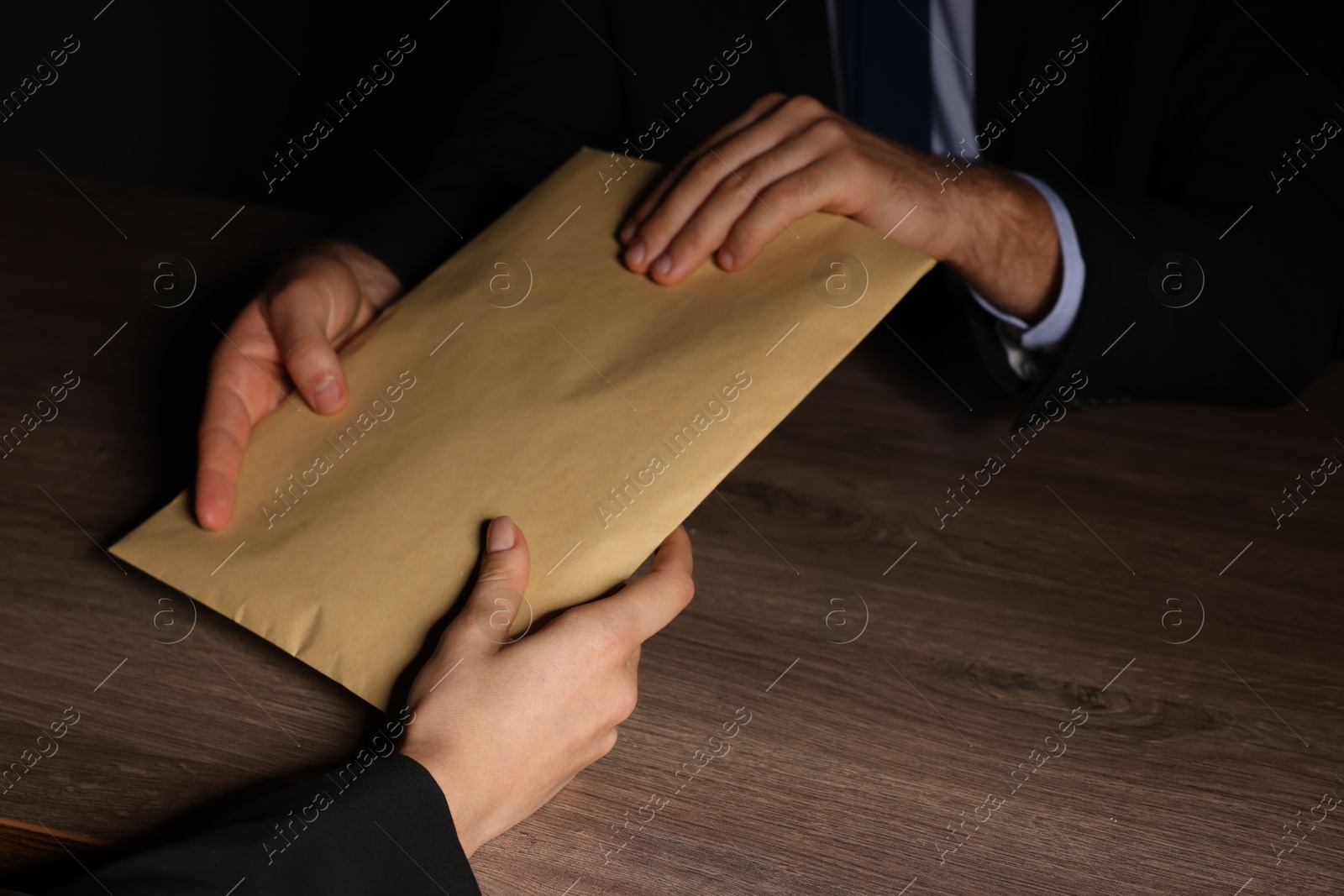 Photo of Corruption concept. Woman giving envelope with money to man at wooden table, closeup