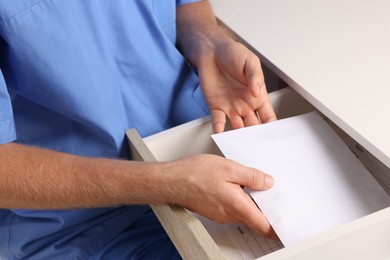 Photo of Corruption concept. Doctor putting envelope with money into drawer, closeup