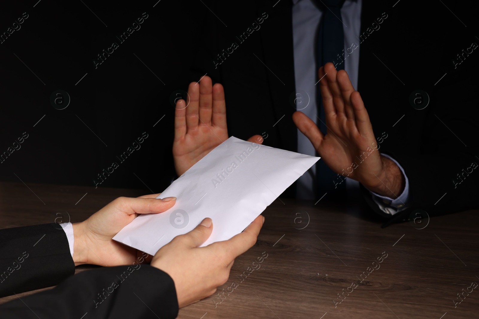 Photo of Corruption concept. Woman giving envelope with money to man at wooden table, closeup