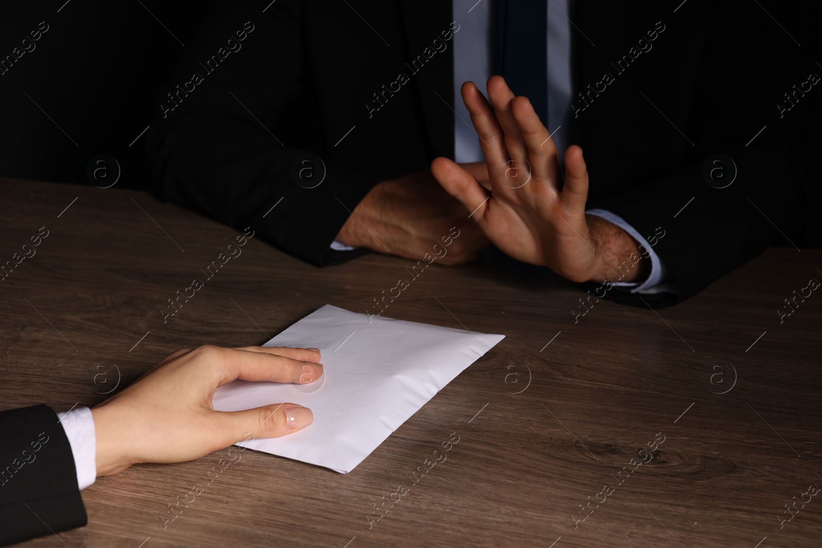 Photo of Corruption concept. Woman giving envelope with money to man at wooden table, closeup