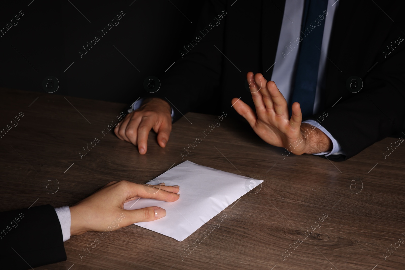 Photo of Corruption concept. Woman giving envelope with money to man at wooden table, closeup