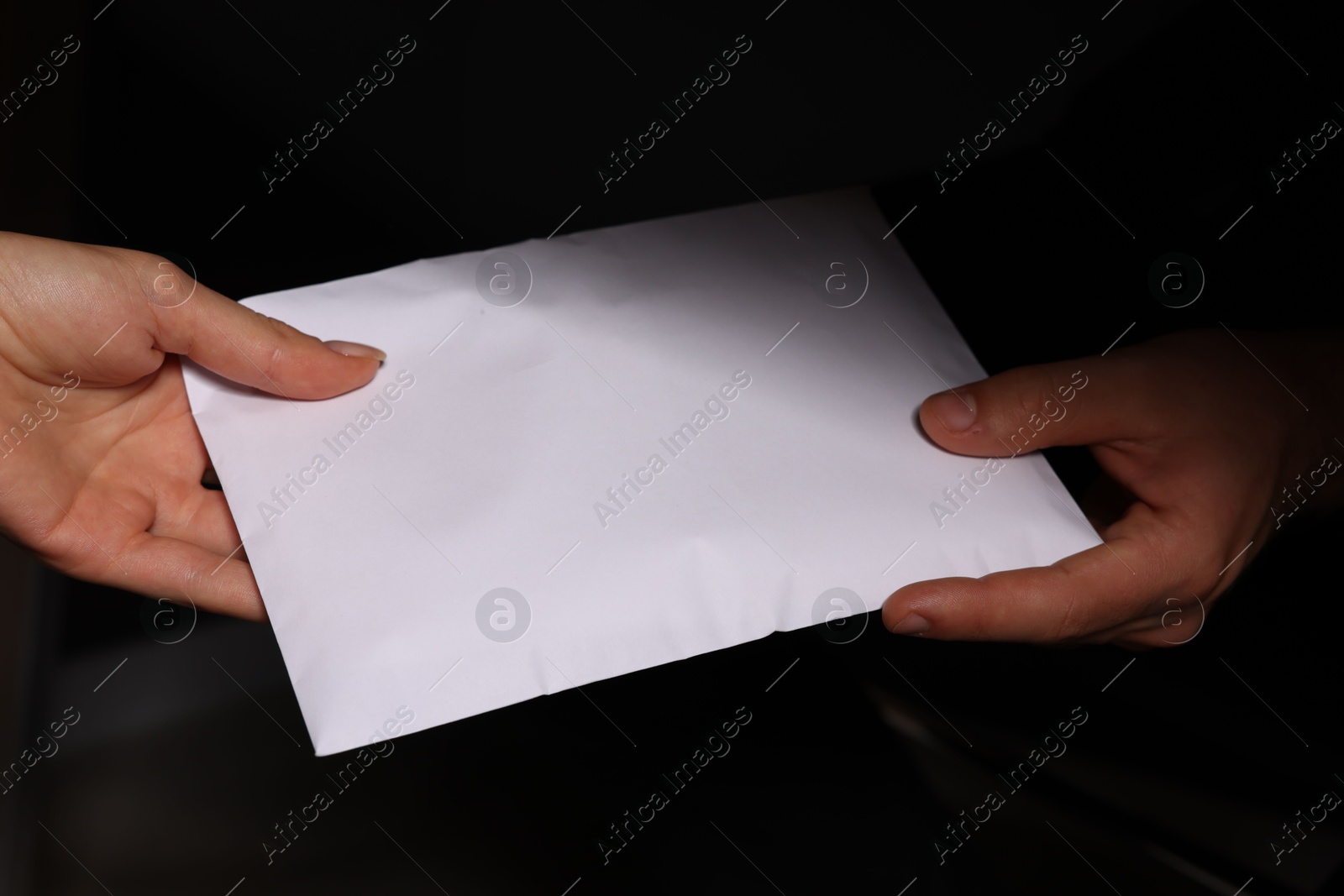 Photo of Corruption concept. Woman giving envelope with money to man on black background, closeup