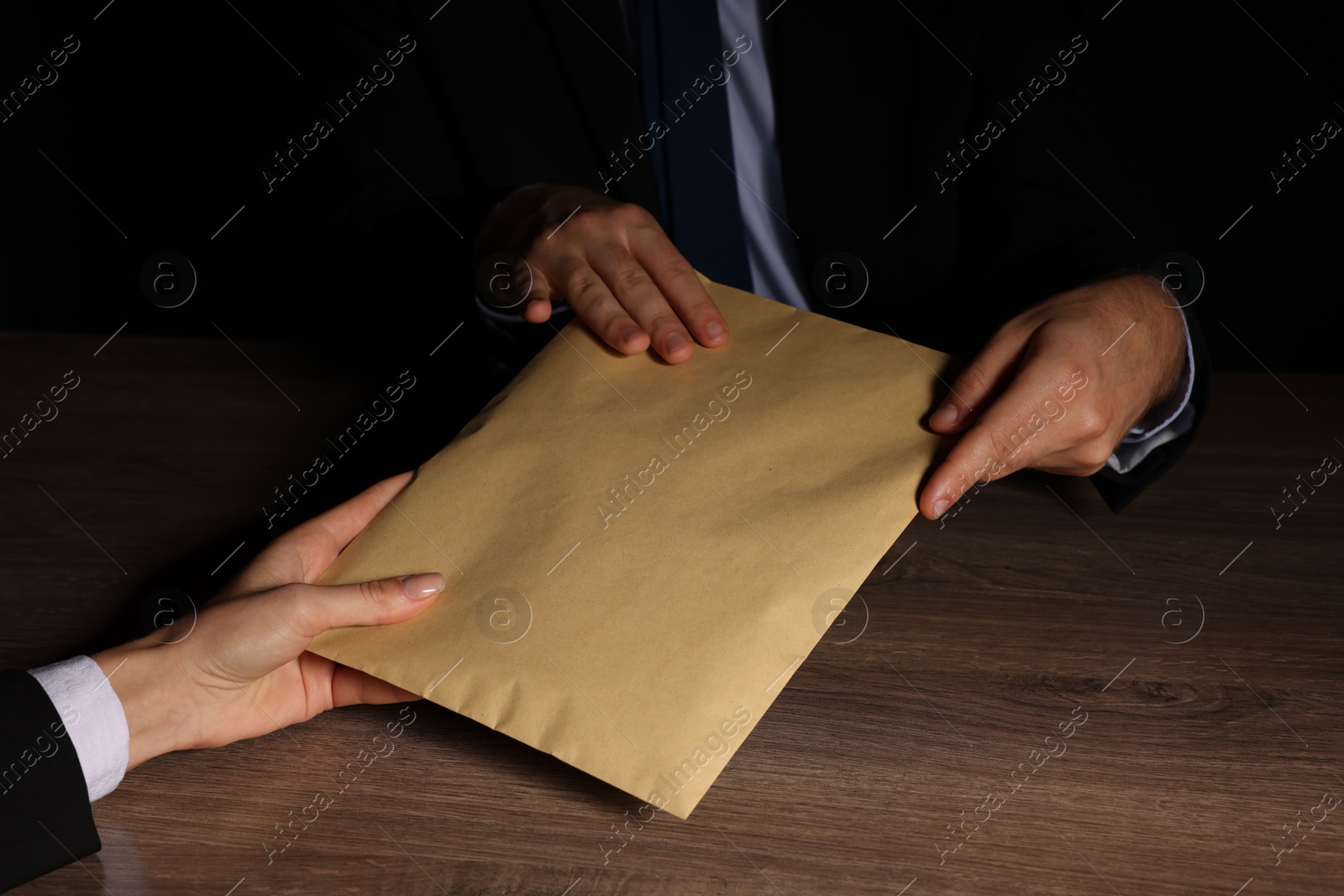 Photo of Corruption concept. Woman giving envelope with money to man at wooden table, closeup