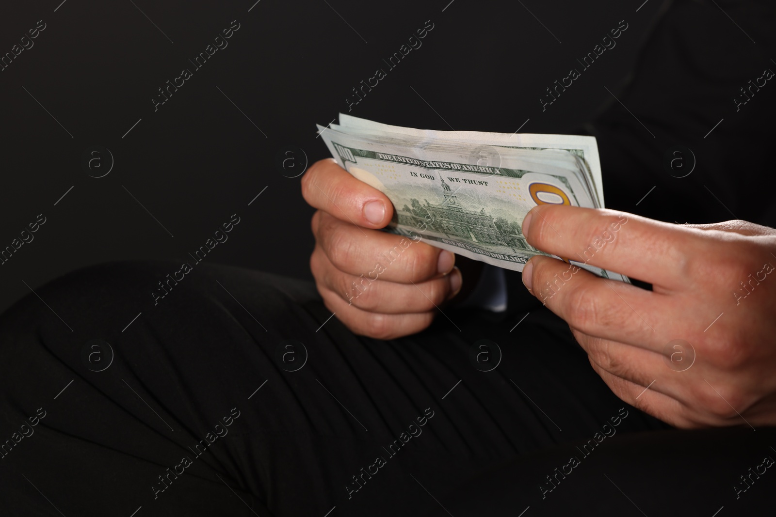 Photo of Corruption concept. Man holding dollar banknotes on black background, closeup. Space for text