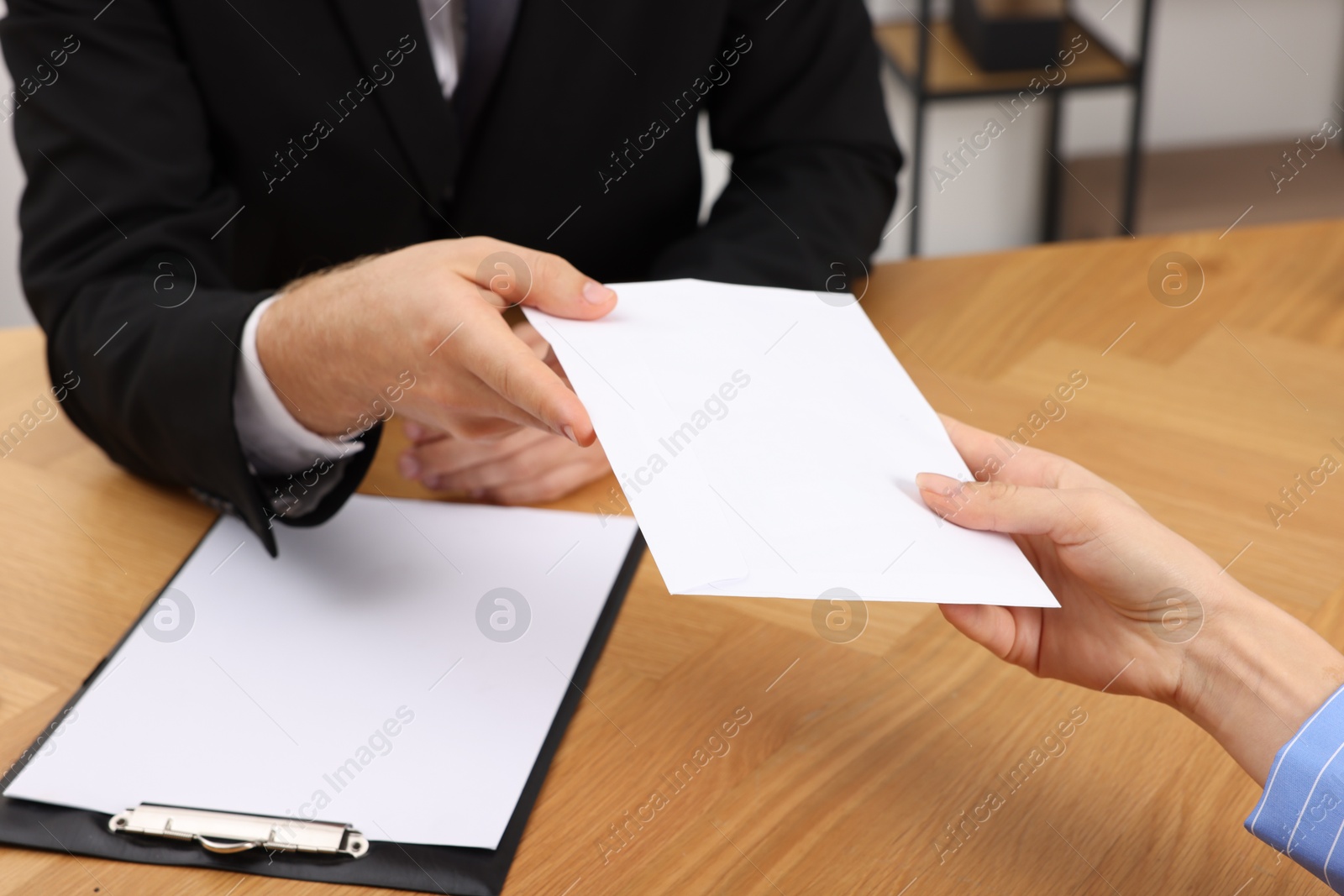 Photo of Corruption concept. Woman giving envelope with money to man at wooden table, closeup