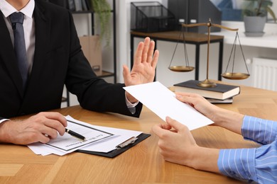 Photo of Corruption concept. Woman giving envelope with money to man at wooden table, closeup