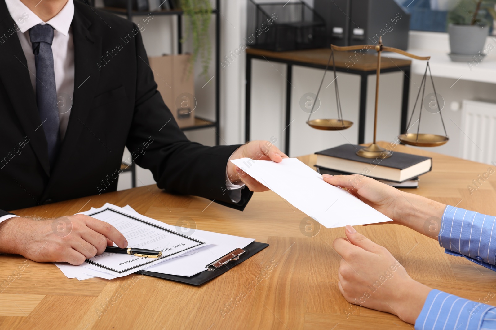 Photo of Corruption concept. Woman giving envelope with money to man at wooden table, closeup