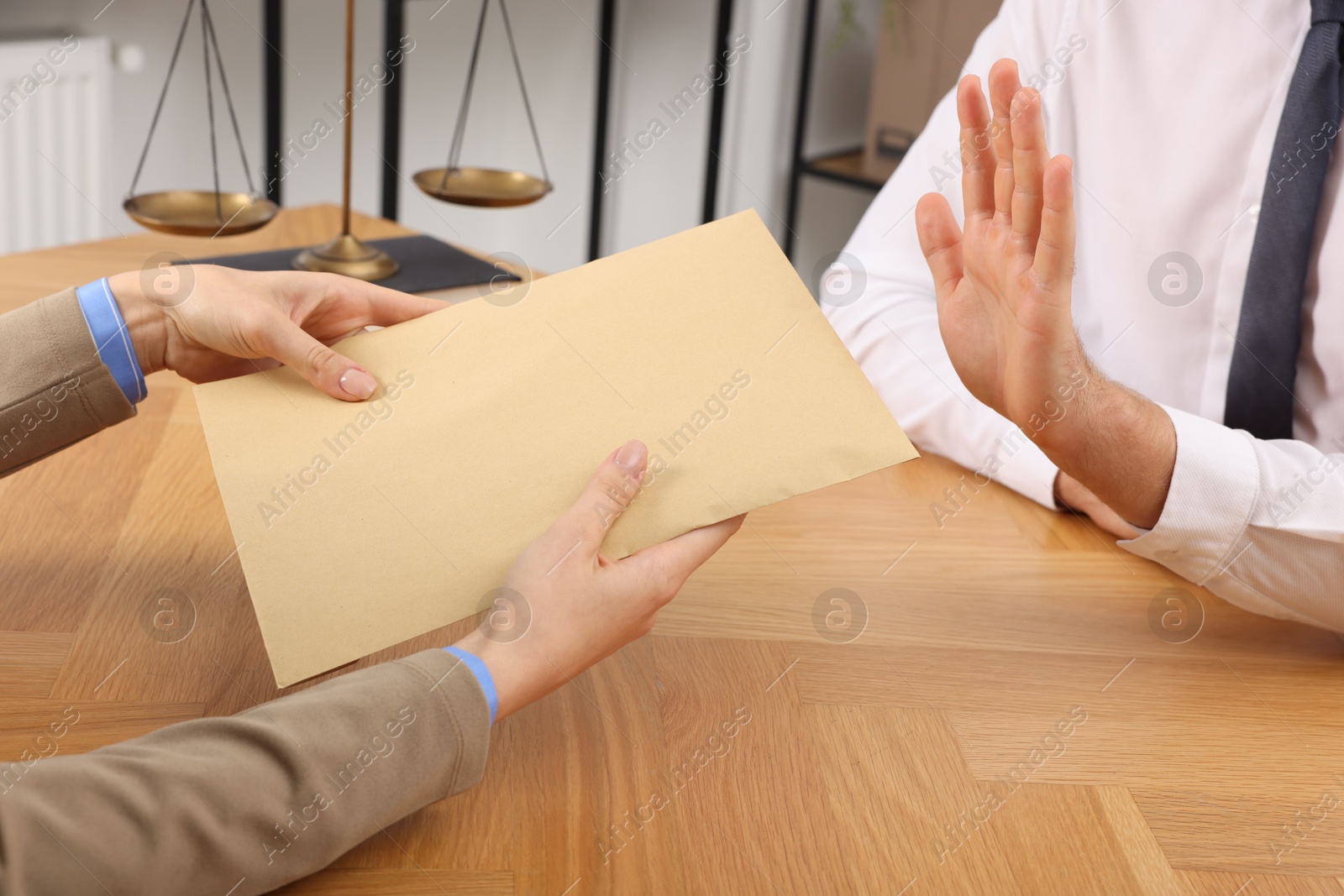 Photo of Corruption concept. Woman giving envelope with money to man at wooden table, closeup