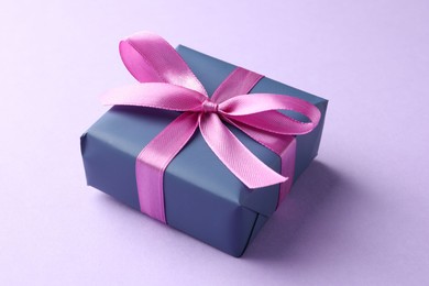 Beautiful gift box with pink bow on violet background