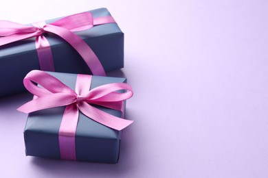 Photo of Beautiful gift boxes with pink bows on violet background, space for text