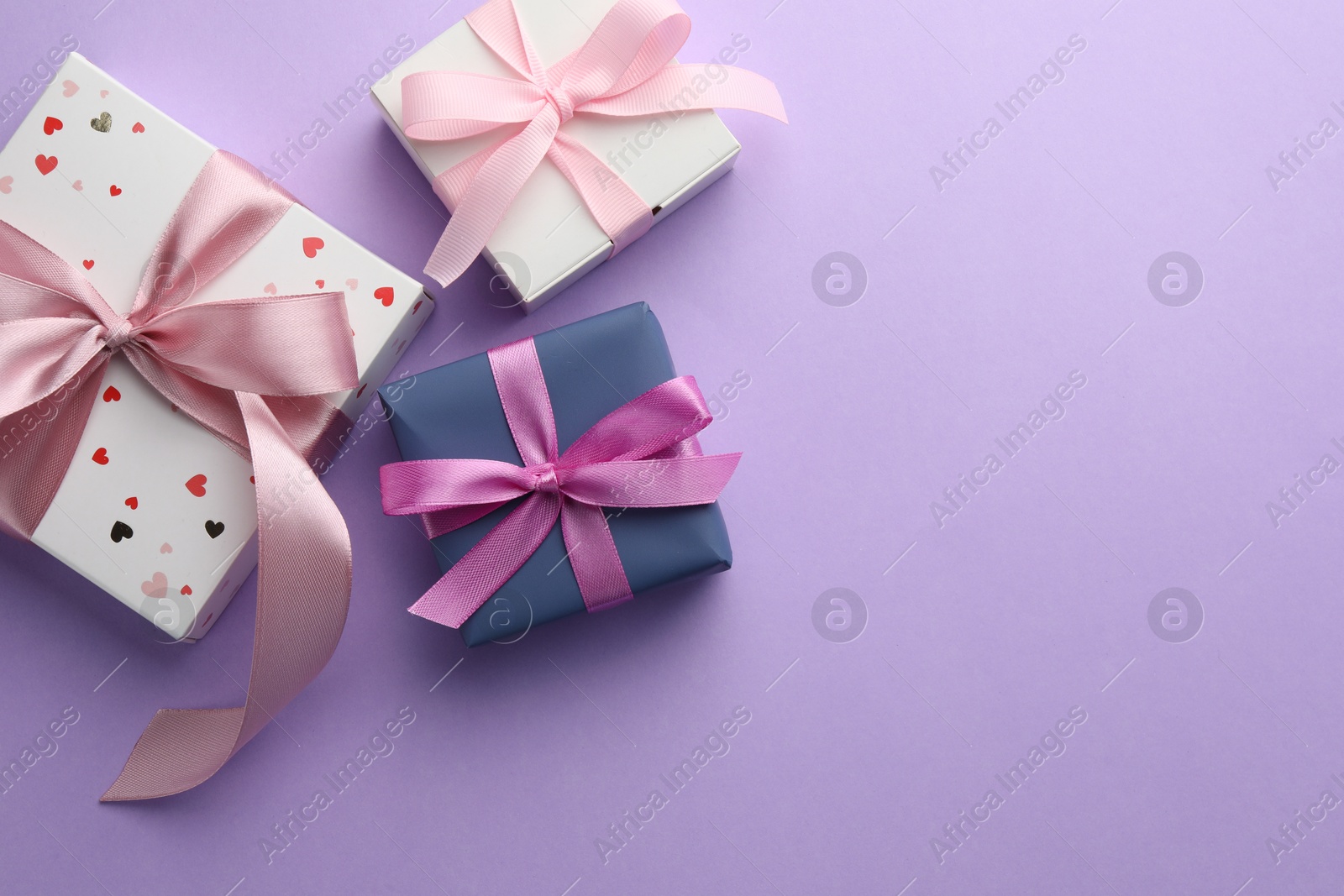 Photo of Beautiful gift boxes with pink bows on violet background, flat lay. Space for text