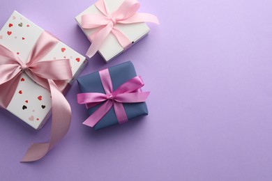 Beautiful gift boxes with pink bows on violet background, flat lay. Space for text