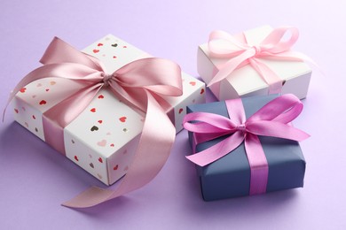 Beautiful gift boxes with pink bows on violet background