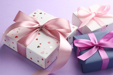 Beautiful gift boxes with pink bows on violet background, closeup