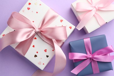 Photo of Beautiful gift boxes with pink bows on violet background, flat lay