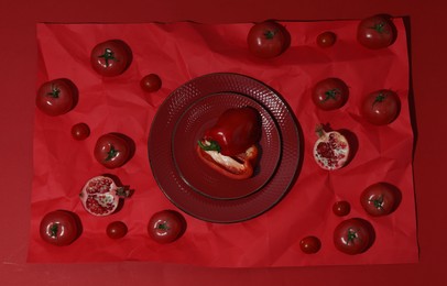 Flat lay composition with pepper, tomatoes and plates on red background