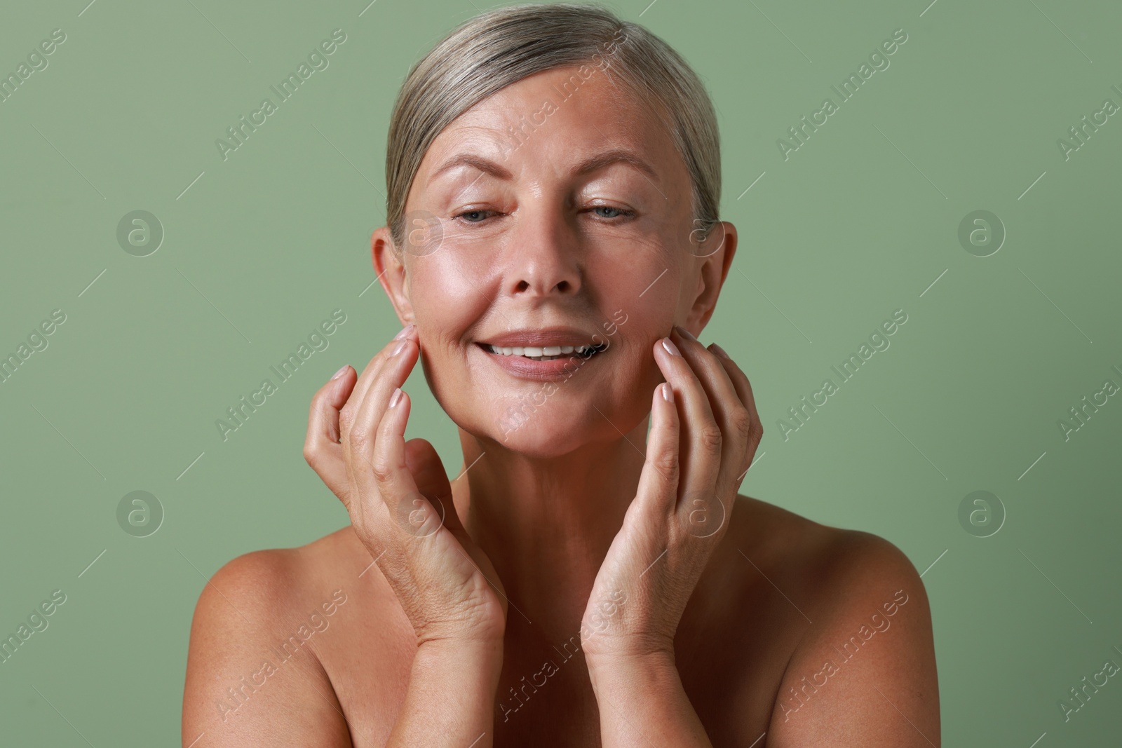 Photo of Face massage. Beautiful woman with healthy skin on light green background