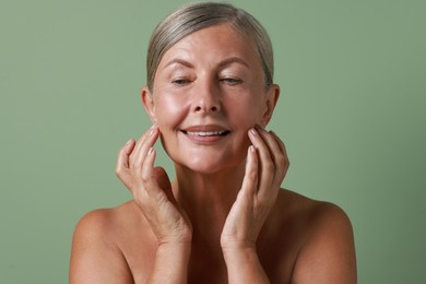 Face massage. Beautiful woman with healthy skin on light green background