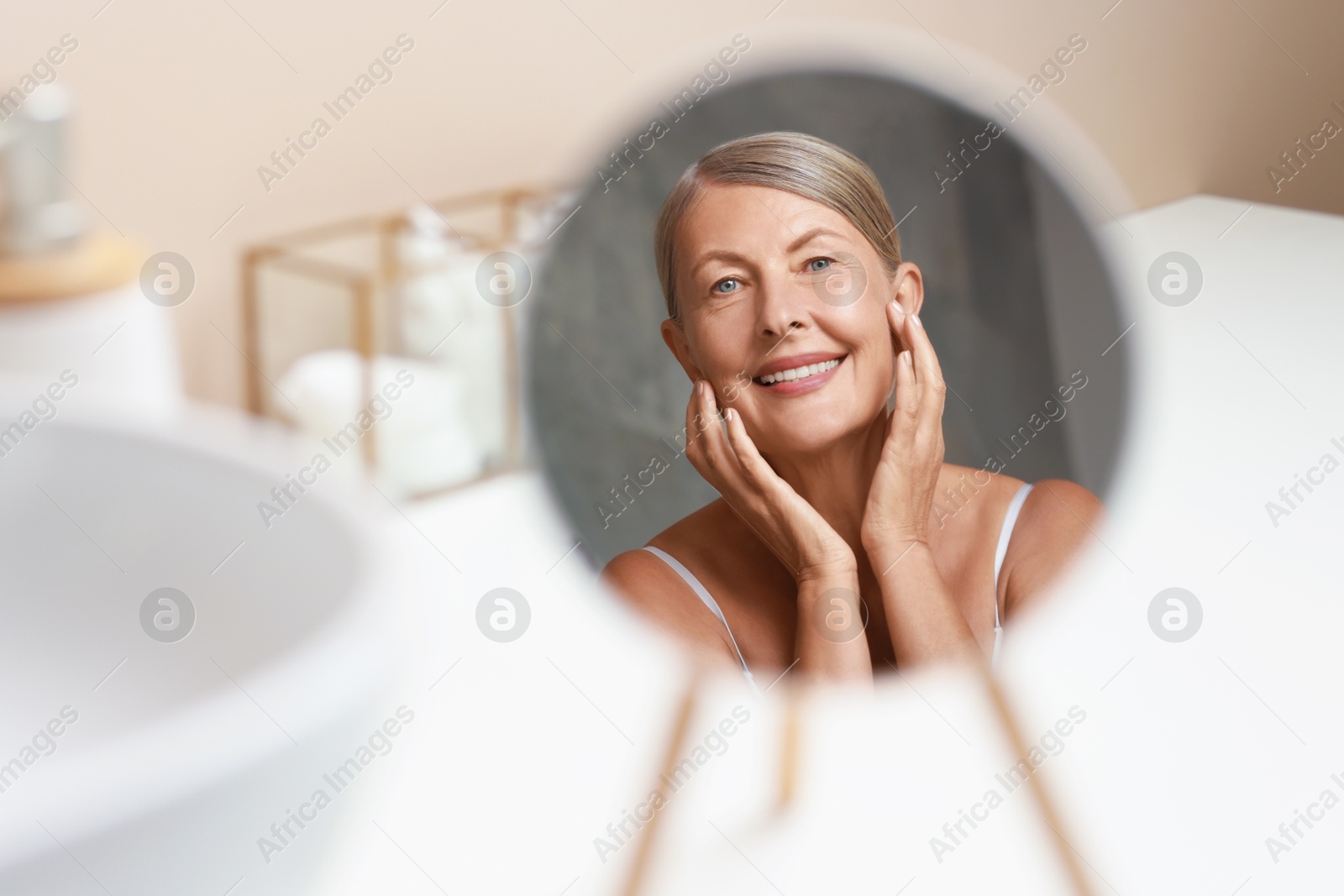 Photo of Face massage. Beautiful woman with healthy skin near mirror at home