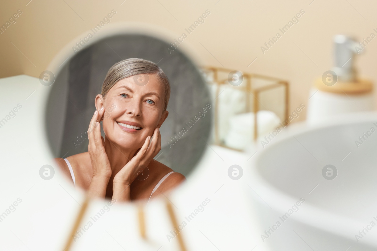 Photo of Face massage. Beautiful woman with healthy skin near mirror at home