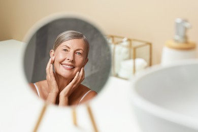 Face massage. Beautiful woman with healthy skin near mirror at home