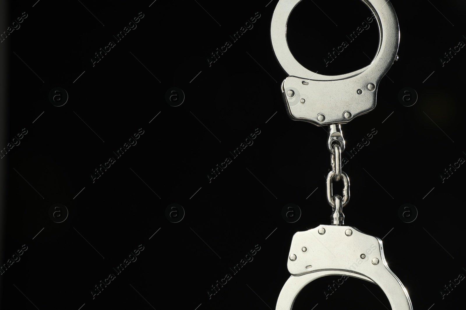 Photo of Metal chain handcuffs on black background, closeup. Space for text