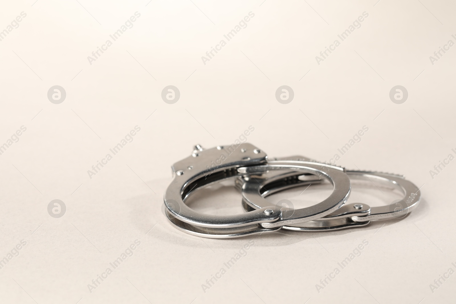 Photo of Metal chain handcuffs on light grey background, closeup. Space for text