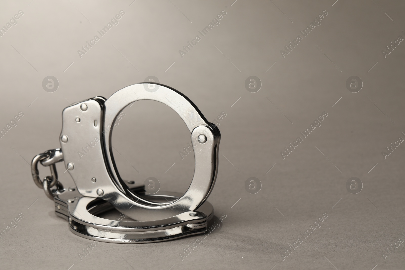 Photo of Metal chain handcuffs on light grey background, closeup. Space for text