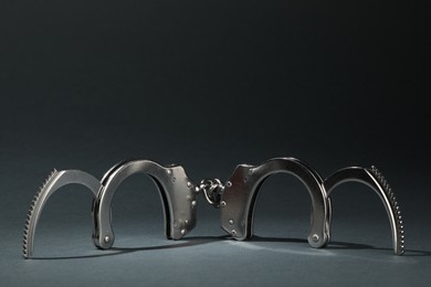 Photo of Metal chain handcuffs on grey background, closeup. Space for text