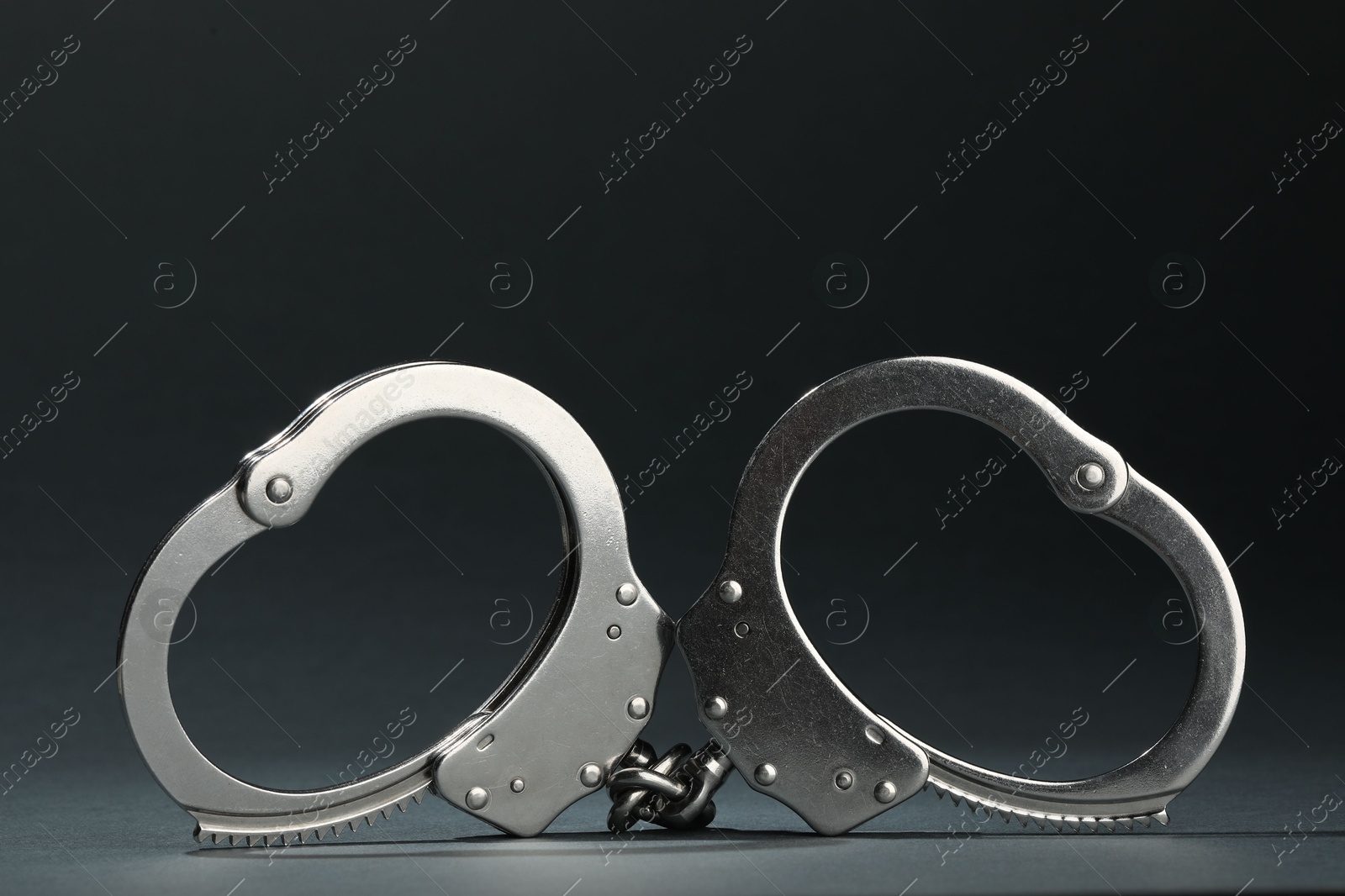 Photo of Metal chain handcuffs on grey background, closeup