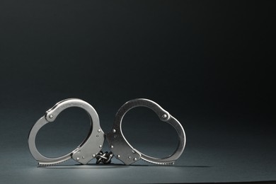 Photo of Metal chain handcuffs on grey background, closeup. Space for text