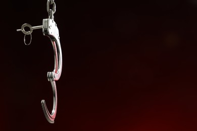 Photo of Metal chain handcuffs on dark background, closeup. Space for text