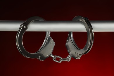 Photo of Metal chain handcuffs on pipe against dark background, closeup